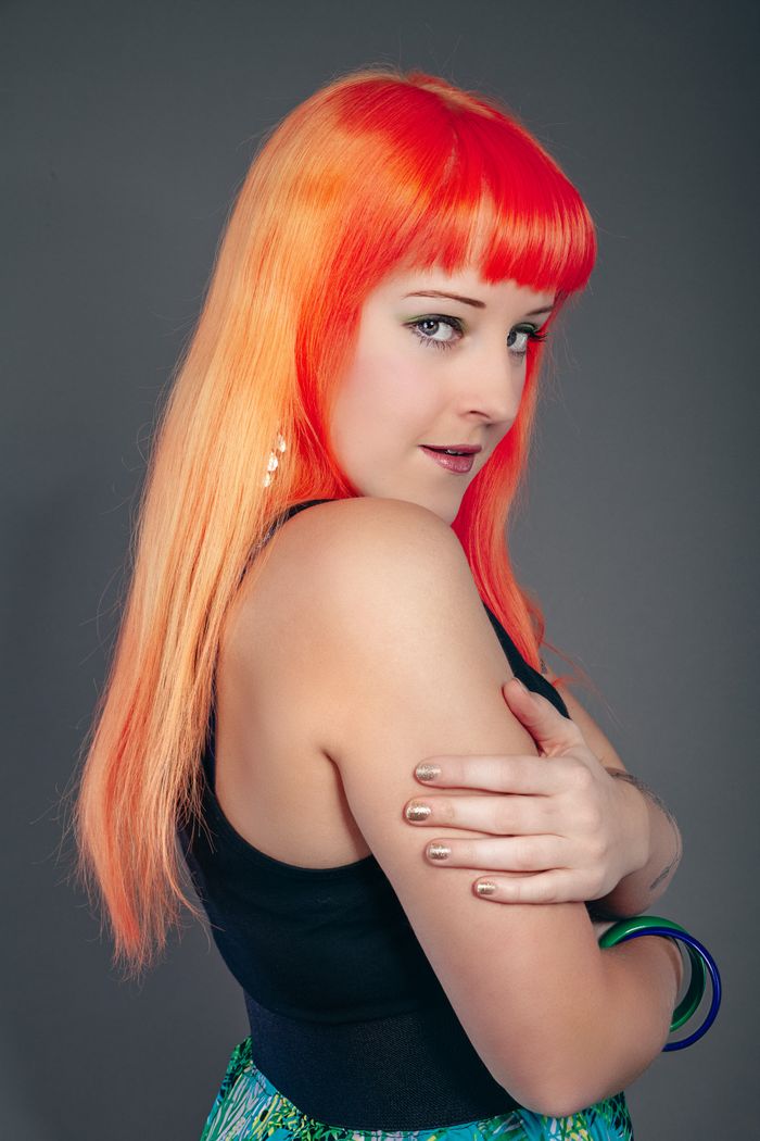 Portrait of a woman with striking orange hair and fashionable accessories.